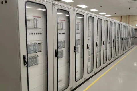 Row of industrial electrical control panels with transparent doors in a clean utility room.