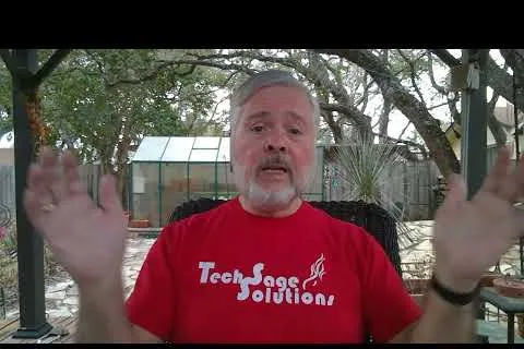 Man in red Tech Sage Solutions shirt speaking outdoors with trees and greenhouse in background