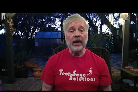 Middle-aged man with gray hair and beard wearing a red TechSage Solutions shirt outdoors at dusk.