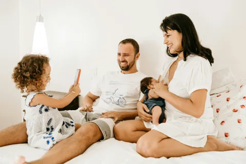 a man and woman sitting on a bed with a baby