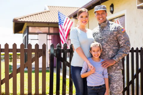 a family standing in front of a fence and a flag