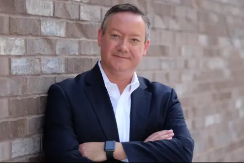 a man in a suit leaning against a brick wall