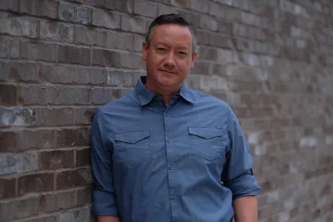 a man standing in front of a brick wall