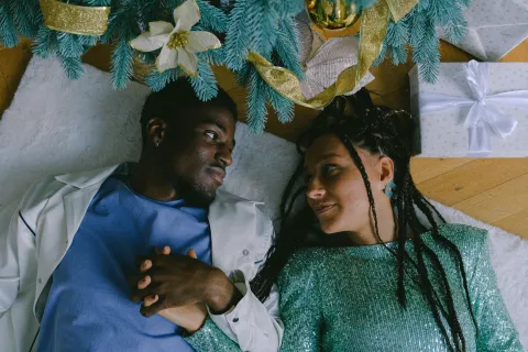a man and woman sitting together under a Christmas tree