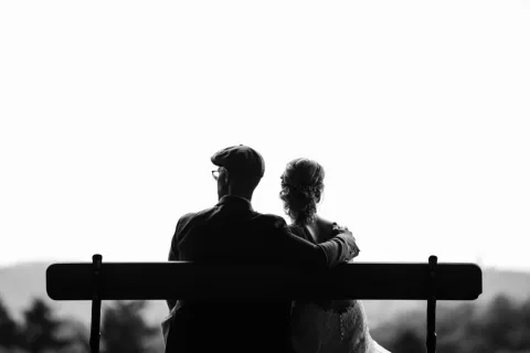a man and woman sitting on a bench under a tree