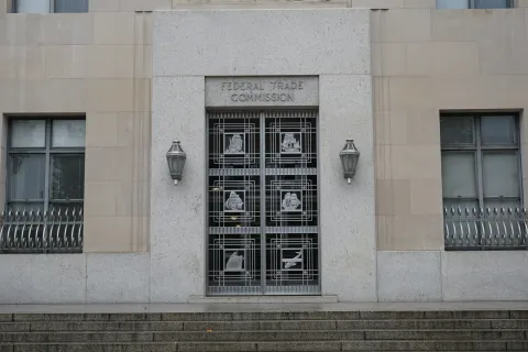 Entrance of the Federal Trade Commission building with ornate metal doors and stone facade.