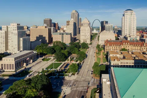 Aerial view of downtown St. Louis with the Gateway Arch in the background on a sunny day.