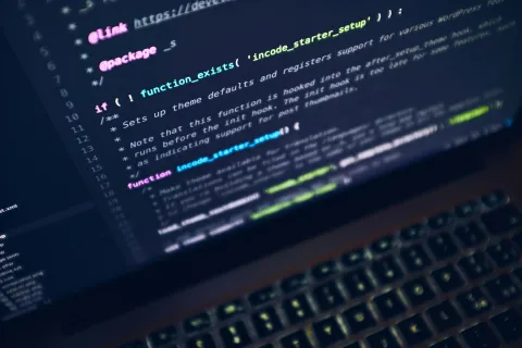 Close-up of a laptop screen displaying colorful programming code for theme setup and functions in a dark interface.