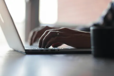 Close-up of hands typing on a laptop keyboard in soft natural light indoors
