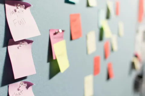 Colorful sticky notes pinned on a bulletin board used for brainstorming and organizing ideas.