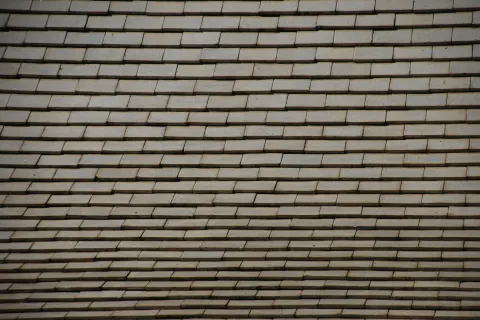 Close-up of a gray tiled roof with evenly spaced rectangular shingles arranged in horizontal rows.