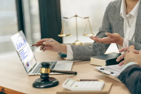 Two professionals discussing legal data analytics on a laptop with a gavel and scales of justice on the desk.