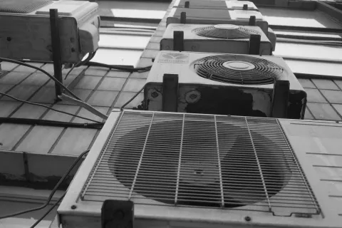 Multiple outdoor air conditioning units mounted on a building wall in a vertical arrangement.