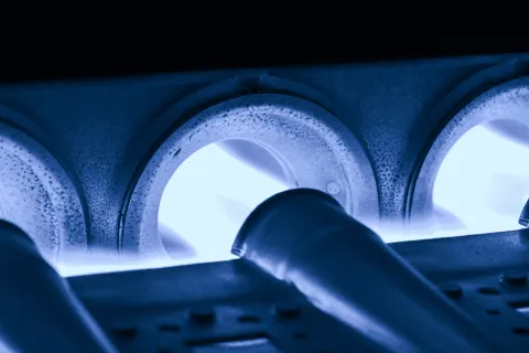 Close-up of blue natural gas flames burning inside a metal stovetop burner.