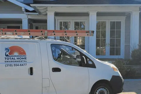 White Total Home Environmental service van with ladder parked in front of a modern house with large windows and balcony.