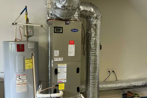 Home HVAC furnace and water heater system with insulated ductwork installed in a garage space.