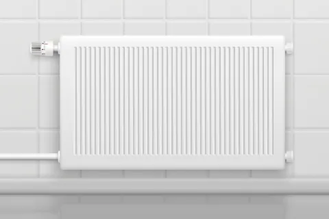 White wall-mounted panel radiator with thermostat valve on tiled background for indoor heating.