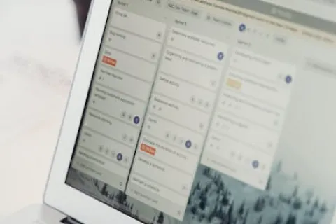 Open laptop displaying a project management tool with task lists and progress tracking on screen.