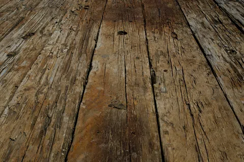 Close-up of weathered wooden planks showing rough textures and natural grain patterns under sunlight.