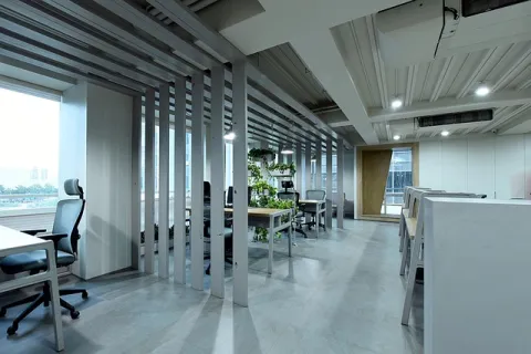 Modern open office space with ergonomic chairs, desks, and natural light through large windows