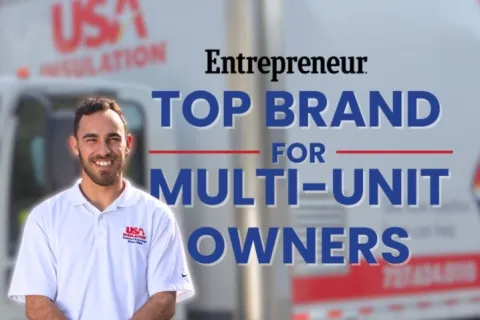 Smiling technician in USA Insulation uniform stands in front of company truck with Entrepreneur top brand award text.