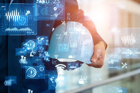 Engineer holding white safety helmet with digital industrial and technology icons overlay in background.