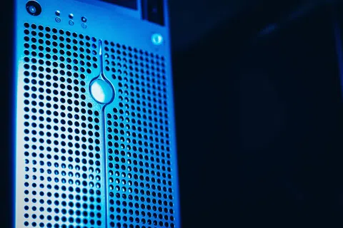 Close-up of a blue-lit computer server tower with perforated metal front panel and control buttons.