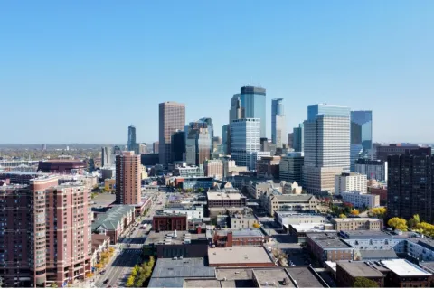 Aerial view of a city skyline with modern skyscrapers under a clear blue sky on a sunny day