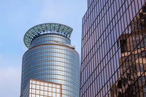 Modern glass skyscrapers with reflective windows under a clear blue sky in an urban cityscape.