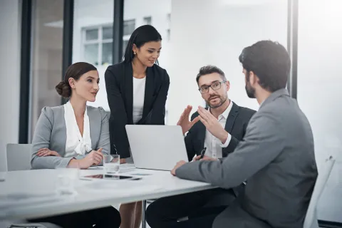 Business team collaborating during a meeting with laptop and documents in a modern office setting.