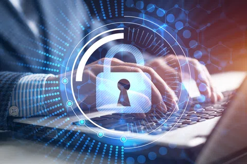 Hands typing on laptop keyboard with digital lock icon and cybersecurity digital effects overlayed.