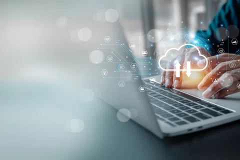 Person typing on laptop with digital cloud computing and data integration icons overlayed