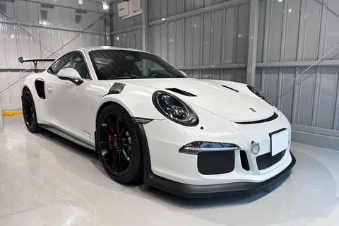 White Porsche 911 GT3 RS sports car with black rims in a bright modern garage showroom.