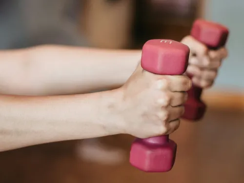 Close-up of hands holding pink dumbbells during a workout