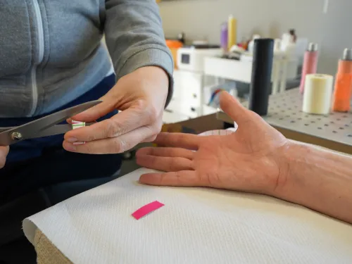 Hand holding scissors cutting taped string near outstretched hand