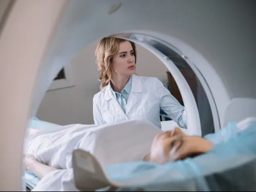 Medical professional operating MRI scanner as patient lies inside the machine for a brain scan.