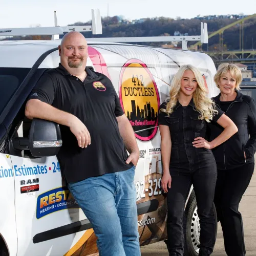 Three professionals standing by a branded 412 Ductless service van near a waterfront with hills in the background