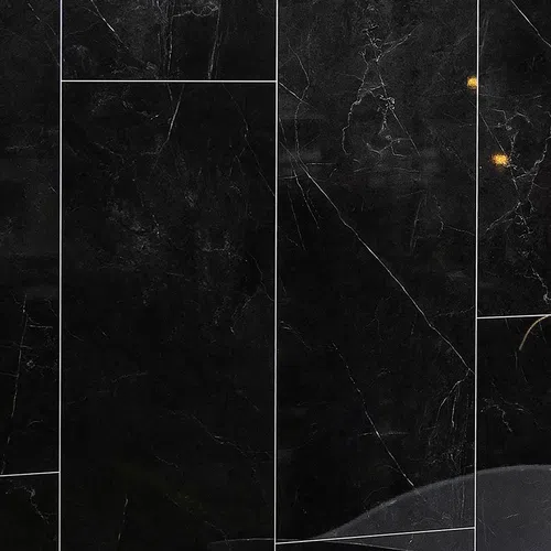 Close-up of black marble tiles with white veins and subtle golden highlights in a polished finish