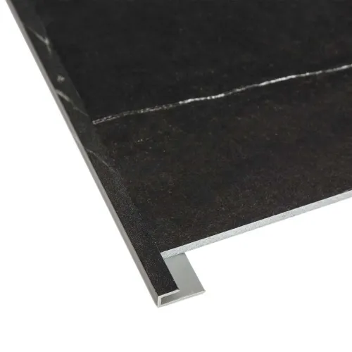 Close-up of black stone tile with metal edge trim on white background highlighting material and finish