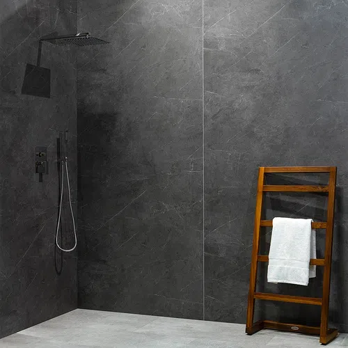 Modern shower area with dark gray stone walls, rainfall showerhead, and wooden towel rack with white towel.