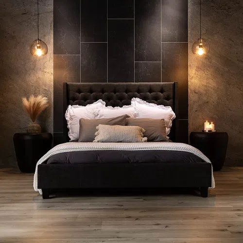 Modern bedroom with dark tufted bed, white and beige pillows, pendant lights, candles, and minimalist decor.