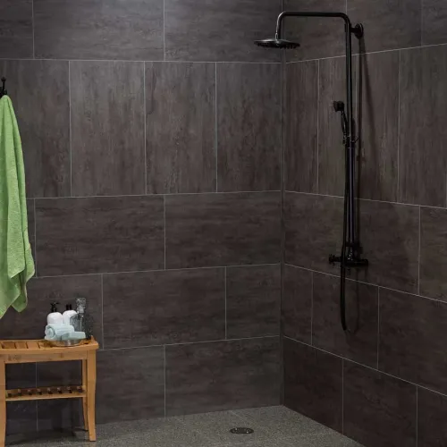 Modern shower area with dark gray tiles, black shower fixtures, wooden stool, and green towel hanging