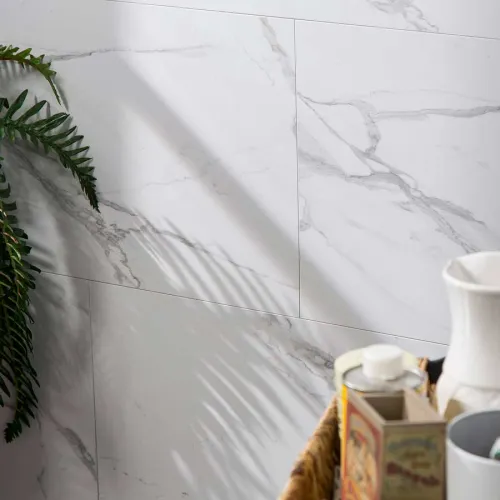Green fern casting shadow on white marble wall tiles with bathroom accessories in wicker basket