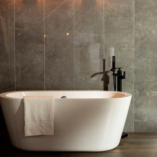 Modern white freestanding bathtub with a towel draped over the edge against a gray marble wall.