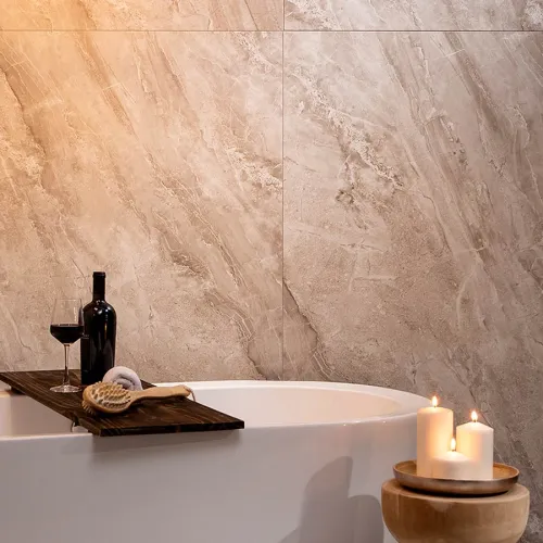 Relaxing bathroom scene with white bathtub, wooden tray holding wine, brush, and candles on stone wall background.