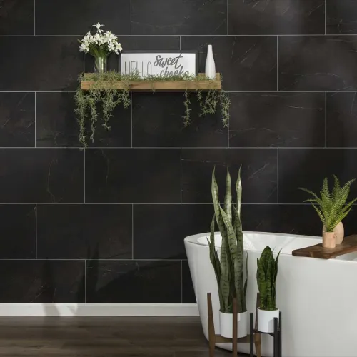 Modern bathroom with dark tile wall, freestanding white tub, wooden floor, floating shelf with plants and decor.
