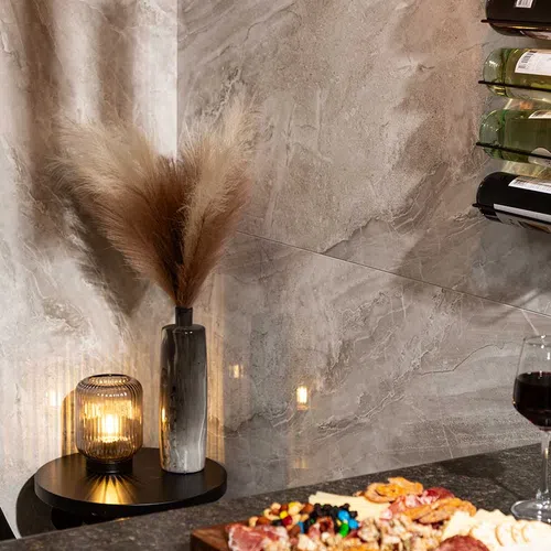 Cozy corner with pampas grass in vase, lit candle, charcuterie board, and wine glass on marble surface