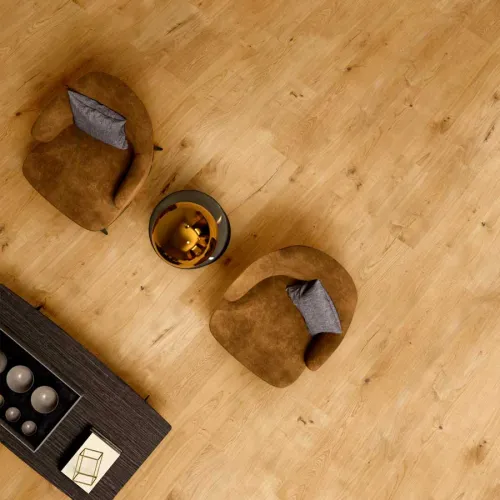 Top view of a cozy seating area with two brown armchairs, gray pillows, a small round table, and wooden floor.