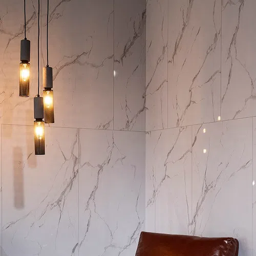 Modern interior with marble-patterned wall tiles and four hanging cylindrical pendant lights with warm glow.
