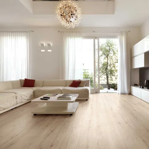 Bright modern living room with beige sectional sofa, white coffee table, large windows, and wooden flooring.